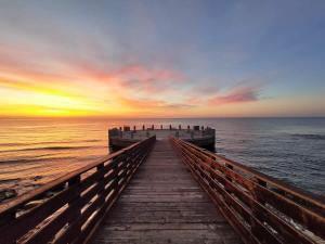 um píer de madeira que leva ao oceano ao pôr do sol em MonoMare em Avola