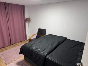 a bedroom with a black bed and a chair at Villa Dielli Gadish in Gnjilane