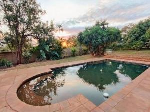 a pool in a yard with a reflection in the water at Ukulala Inn in Malelane