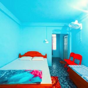 a blue bedroom with a bed and a red chair at Zinnia Homestay in Cherrapunji