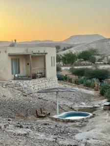 a house in the desert with a pool and an umbrella at Amara Escape in Zuqim