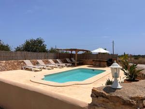a swimming pool with lounge chairs and an umbrella at Can Mariano Mayans in Sant Francesc Xavier