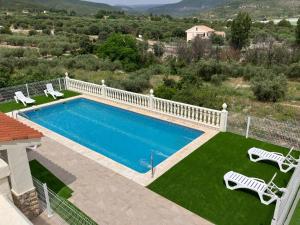 an image of a swimming pool with two lawn chairs at Casa Gregal CR Los Cuatro Vientos in Moratalla