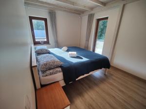 a bedroom with a bed with a blue blanket and two windows at River Mind Villa with SPA in Zalioji