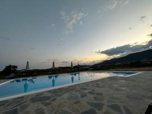 a swimming pool with the sunset in the background at Petra Nova Suites in Nea Peramos
