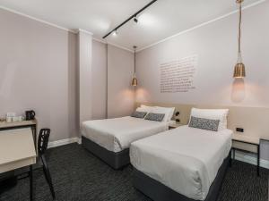 ein Zimmer mit zwei Betten und einem Schreibtisch und einem Tisch in der Unterkunft Nightcap at Belgian Beer Cafe in Perth