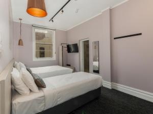 ein Hotelzimmer mit zwei Betten und einem Fernseher in der Unterkunft Nightcap at Belgian Beer Cafe in Perth