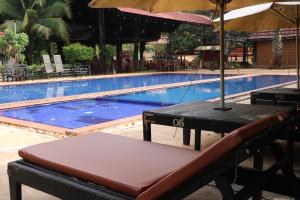 una piscina con una panchina e un ombrellone di Phum Khmer Resort a Banlung