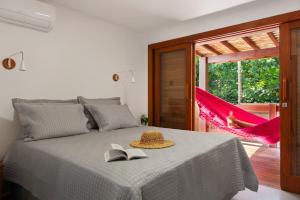 a bedroom with a bed with a book and a hat at Chalé Coruja - Taipu com Piscina in Marau