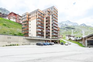 a large building with cars parked in a parking lot at Appartement 6p Au Pied Des Pistes in Val Thorens