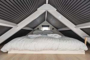 ein Schlafzimmer mit einem großen weißen Bett im Dachgeschoss in der Unterkunft Flamingo Beach Apartments in Zandvoort