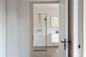ein Badezimmer mit Dusche mit Glastür in der Unterkunft Flamingo Beach Apartments in Zandvoort