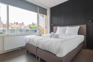 ein Schlafzimmer mit einem großen Bett mit einem großen Fenster in der Unterkunft Flamingo Beach Apartments in Zandvoort