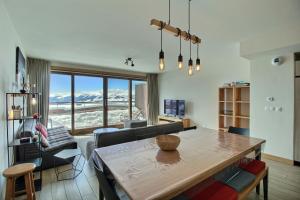 a living room with a dining room table with a view at ARC 1600, LE RIDGE, Appartement 10 personnes Duplex Vue Montagne - ski aux pieds - Sauna, Hammam, Piscine, Salle de salle de sport-fitness in Arc 1600