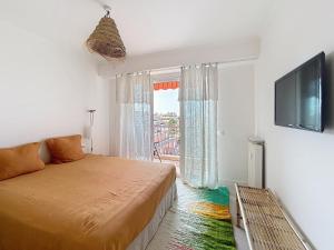a bedroom with a bed and a tv and a window at Azur in Cagnes-sur-Mer