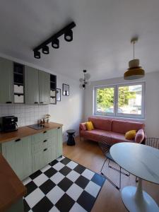 a living room with a red couch and a kitchen at Dębina Lounge 20 Apartamenty in Debina