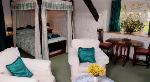 a living room with two white chairs and a bed at Budleigh Farm Cottages in Moretonhampstead