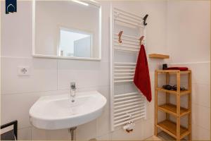 ein weißes Badezimmer mit Waschbecken und Spiegel in der Unterkunft Villa Martha Apartment 3 in Heringsdorf
