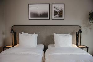 two beds with white sheets and two pictures on the wall at Home Hotel Etage in Västerås