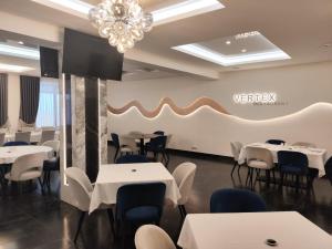 a restaurant with white tables and chairs and a chandelier at Готель-ресторан Vertex in Tyachiv
