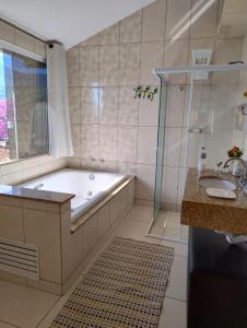 a bathroom with a tub and a sink and a shower at Pousada Aconchego in Passa Quatro +26 photos