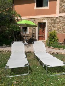 two empty beds in the grass with a green umbrella at Ina Maka - Appartamento con giardino immerso nel verde in Mengara