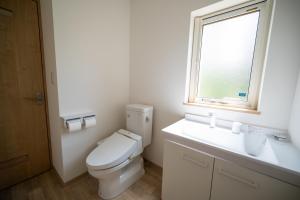 a bathroom with a toilet and a sink and a window at 冬のソナタ1 in Nakafurano