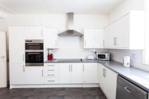 a white kitchen with white cabinets and appliances at No 13 Georgian Shared House - By Clifton Short Lets in Bristol