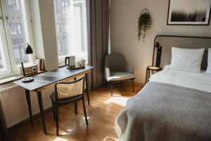 a bedroom with a desk and a bed and a table and chairs at Home Hotel Etage in Västerås