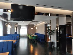 a waiting room with blue chairs and a flat screen tv at Готель-ресторан Vertex in Tyachiv