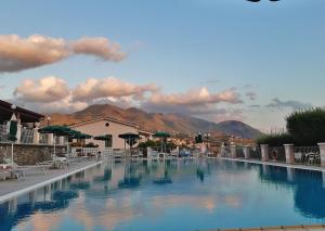 a large swimming pool with chairs and mountains in the background at Hotel Ristorante Borgo La Tana in Maratea