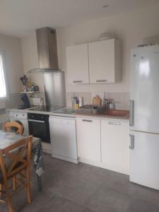 a kitchen with white cabinets and a white refrigerator at APPARTEMENT PRES DE ROYAN 7 MINUTES MER CONFORT CALME rdc espace détente jardin in Sémussac +12 photos