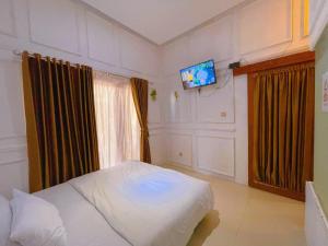 a bedroom with a bed and a flat screen tv at Rafitha Exclusive in Demangan