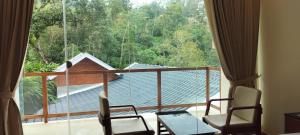 ムンナルにあるGMG Gardens Homestay Munnarのバルコニー(椅子付)、大きな窓が備わる客室です。