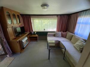 a living room with a white couch and a television at Domki holenderskie na Mazurach in Dźwierzuty