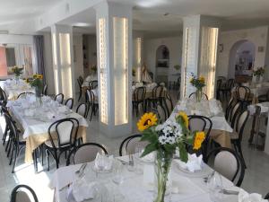 a dining room with white tables and chairs with flowers at Hotel Ristorante Borgo La Tana in Maratea