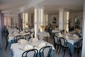 a dining room with white tables and black chairs at Hotel Ristorante Borgo La Tana in Maratea