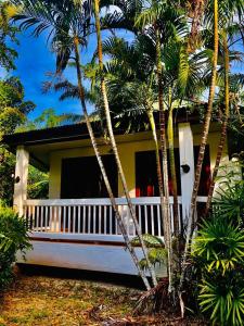 ein gelb-weißes Haus mit Palmen davor in der Unterkunft The Emerald Krabi Beach Resort in Klong Muang Beach