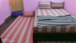 two twin beds in a room with striped walls at Shree chendur Rooms stay in Tiruvannāmalai