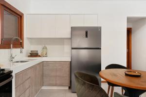 a kitchen with a stainless steel refrigerator and a table at Casa Carcará a 300 m da praia de Taipu de Fora in Taipu