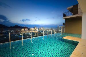 a swimming pool on top of a building with a city skyline at Plus Sriracha in Si Racha