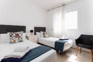 1 Schlafzimmer mit 2 Betten und einem schwarzen Stuhl in der Unterkunft MTR - Marbella Temporary Rent Two Bedrooms Apartment Av del Mar in Marbella + 23 Fotos