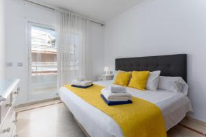 ein weißes Schlafzimmer mit einem großen Bett und gelben Kissen in der Unterkunft MTR - Marbella Temporary Rent Two Bedrooms Apartment Av del Mar in Marbella