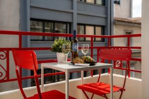 stół z dwoma krzesłami, butelką wina i kieliszkami w obiekcie Garment District Suites w Atenach