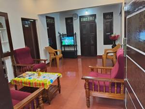 a living room with chairs and a table and a tv at UD- VAS home stay in Varkala