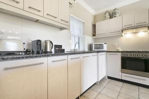 a large kitchen with white cabinets and appliances at Winelands Golf Lodges 4 in Stellenbosch +34 photos