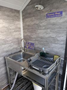 a kitchen sink with a strainer in it at Budget stay, in lovely private setting with rustic charm, log burner, fire pit, campers kitchen & Eco Loo NO BEDDING SUPPLIED in Narberth