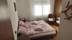 a bedroom with a bed with a pink comforter and a window at Sobe Godina in Materija