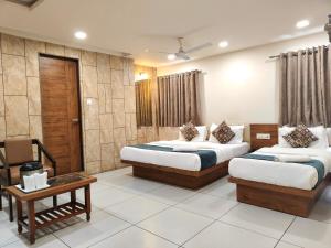 a hotel room with two beds and a table at Hotel Kinara in Ahmedabad