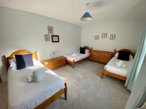 a bedroom with two beds and two chairs in it at Killick Cottage in Sidmouth